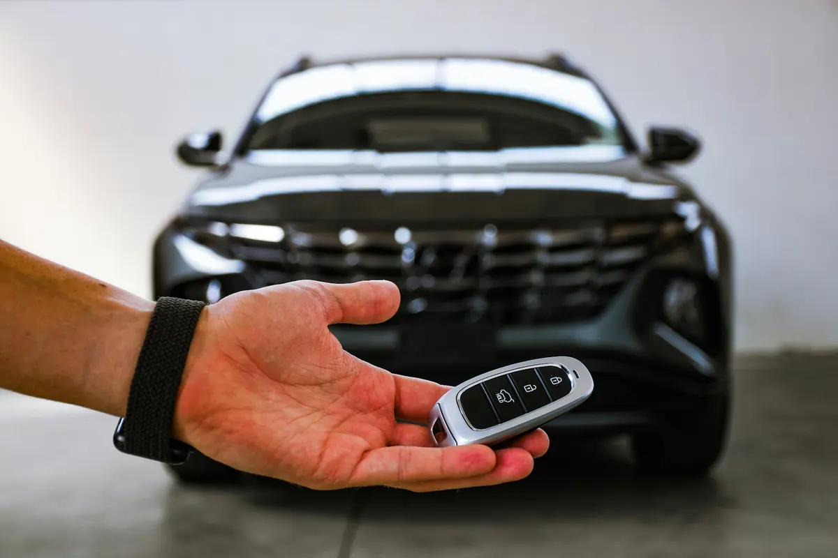 Car key being handed over in front of an SUV