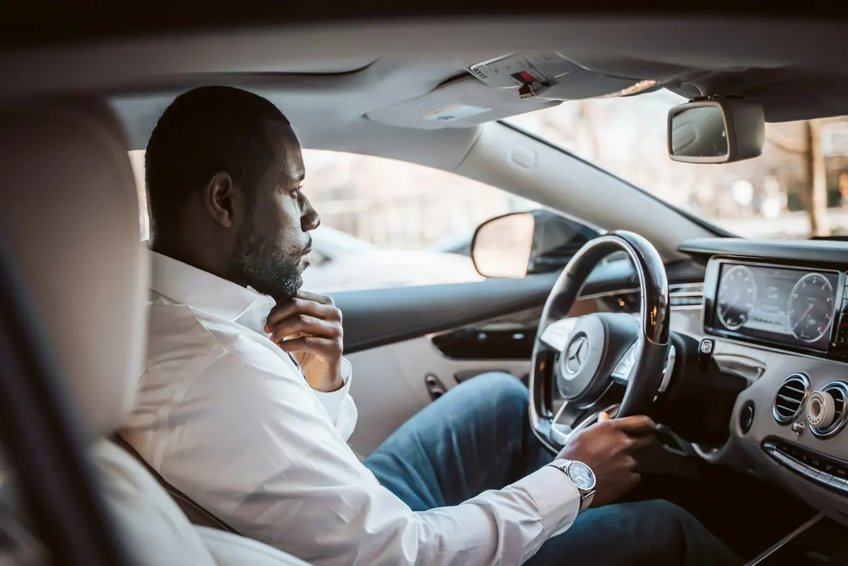 Chauffeur in a white shirt driving a client car in Accra