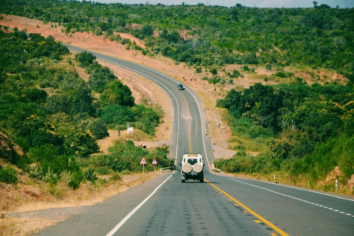 Four-wheel-drive vehicle on a highway through green hills
